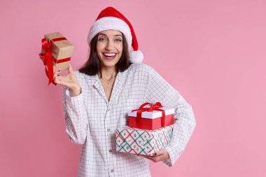 Pembe arka planda Noel Baba şapkalı mutlu kadın.