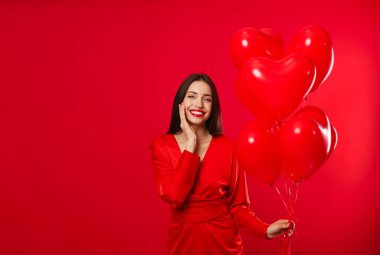 Sevgililer Günü. Kırmızı arka planda kalp şeklinde balonları olan güzel bir kadın. Metin için boşluk