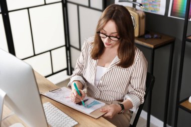 Tasarımcı ofisteki ahşap masada kıyafet çizimi yapıyor.