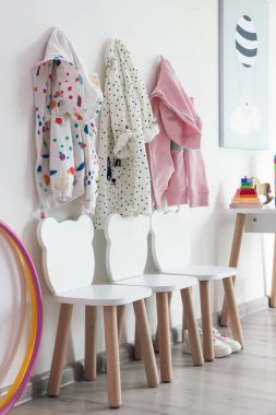 Oyun odasındaki ışıklı duvarda şık sandalyeler ve elbiseler asılı. İç tasarım