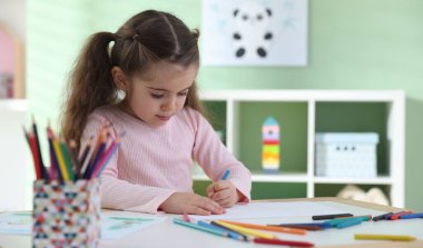 Masada pastel boyayla resim çizen sevimli küçük kız. Metin için boşluk