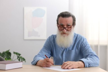 Ahşap masada son dilek ve vasiyetnameyi imzalayan kıdemli bir adam.