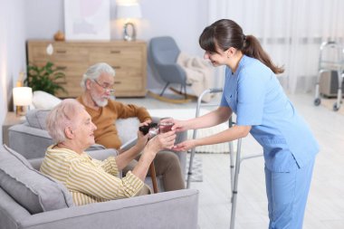 Huzurevindeki yaşlı kadına bir bardak su veren bakıcı.