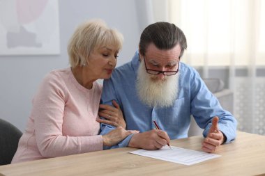 Ahşap masada son arzuları ve vasiyetnameleri imzalayan yaşlı çift.
