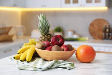Mutfaktaki beyaz mermer masada farklı taze meyveler.