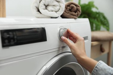 Beyaz çamaşır makinesini çalıştıran kadın, yakın plan.