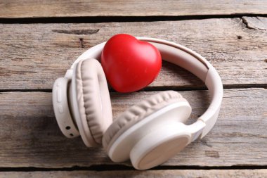 Kulaklıklar ve kalp figürü ahşap masada, yakın plan.