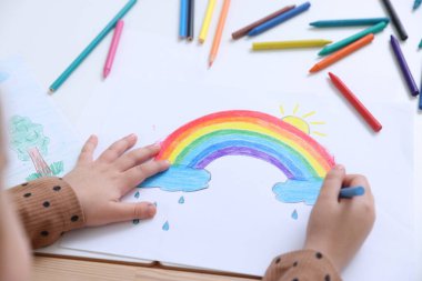 Masada kalemle çizen küçük kız, yakın plan.