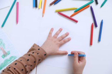 Masada kalemle çizim yapan küçük bir kız.