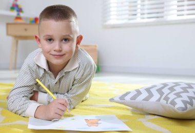 Evde yerde kalemle resim yapan şirin bir çocuk. Metin için boşluk