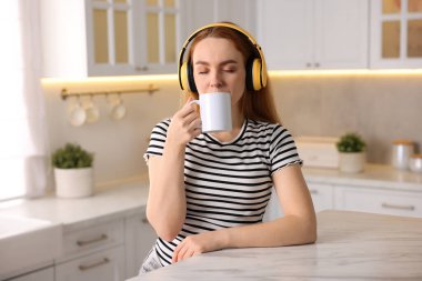 Kahveli kadın mutfakta müzik dinliyor.