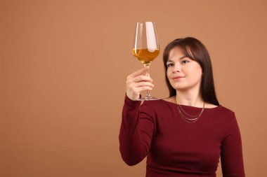 Soluk kahverengi arka planda beyaz şarap kadehi olan profesyonel şarap garsonu.