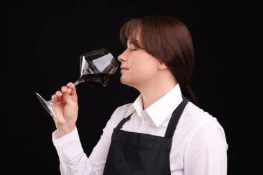 Profesyonel şarap garsonu siyah arka planda kırmızı şarap tadıyor.