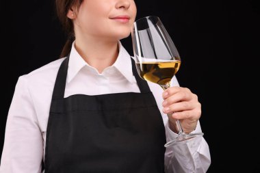 Profesyonel şarap garsonu siyah arka planda beyaz şarap tadıyor.