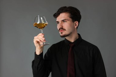 Gri arka planda beyaz şarap kadehi olan profesyonel şarap garsonu.