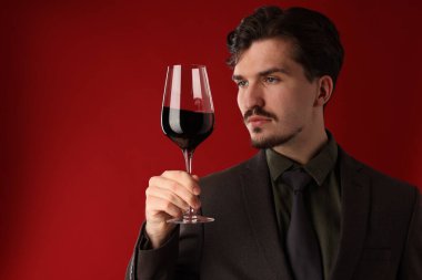 Kırmızı arka planda şarap kadehi olan profesyonel bir şarap garsonu. Metin için boşluk