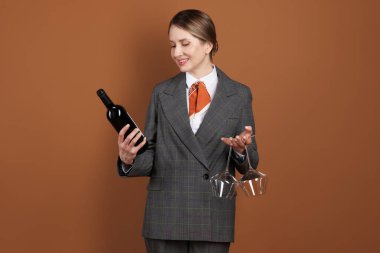 Kahverengi arka planda şarap ve gözlüklü profesyonel şarap garsonu.