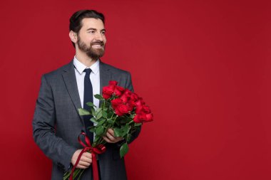Sevgililer Günü. Kırmızı arka planda gül buketi olan yakışıklı bir adam. Metin için boşluk