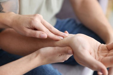 Kadın adamın nabzını kontrol ediyor. Parmakları evde, yakın plan.