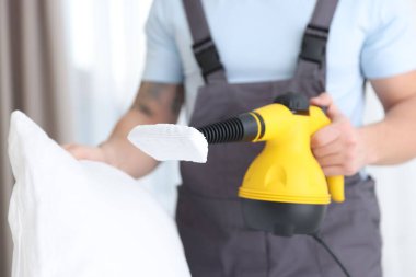 Haşere kontrol görevlisi yastığı temizliyor, kapalı alanda temizliyor, yakın plan.