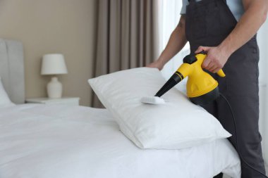 Haşere kontrol görevlisi yastığı temizliyor, kapalı alanda temizliyor, yakın plan. Metin için boşluk