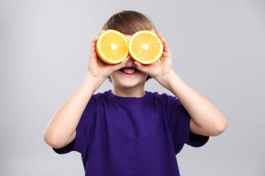 Gri arka planda taze turuncu kesilmiş çocuk.