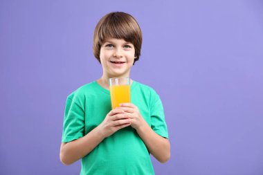 Menekşe arka planında bir bardak taze portakal suyu olan çocuk. Metin için boşluk