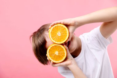 Pembe arka planda taze kesilmiş turuncu çocuk.