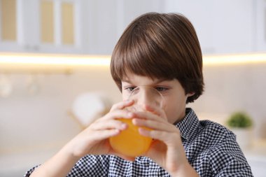 Çocuk evde taze portakal suyu içiyor.