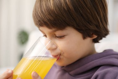 Çocuk evde taze portakal suyu içiyor.