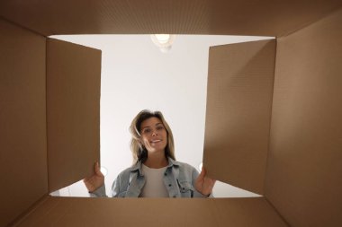 Kadın içerideki karton kutuya bakıyor, içerideki paketi görüyor.