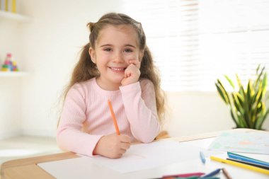 Masada kalemle çizen sevimli küçük kız.