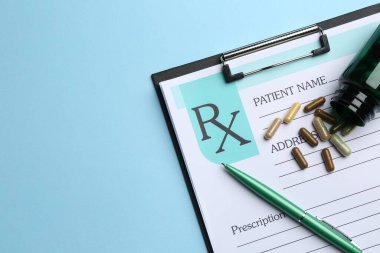 Açık mavi arka planda boş tarlalar, haplar ve kalemle yazılmış tıbbi reçete formu. Metin için boşluk