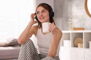 Kahveli güzel bir kadın evde müzik dinliyor.