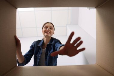 Kadın içerideki karton kutuya bakıyor, içerideki paketi görüyor.