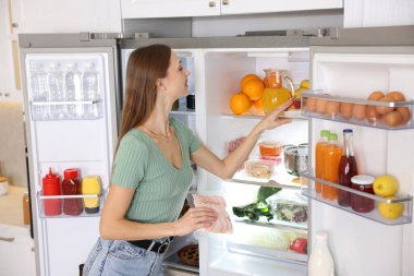 Mutfakta jambonlu kadın açık buzdolabının yanında.