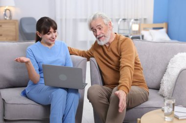 Bakıcı, huzurevinde dizüstü bilgisayar kullanmayı öğretiyor.