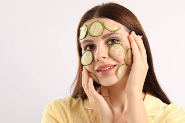 Yüzünde salatalık dilimleri olan bir kadın beyaz arka planda, mesaj için yer var.