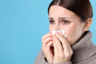 Açık mavi arka planda burnu akan bir kadın, yakın plan ve mesaj için yeri var. Soğuk Semptom