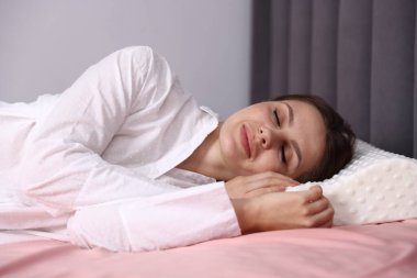 Evde ortopedik yastıkla uyuyan genç bir kadın. Sağlıklı duruş