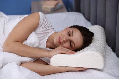 Evde ortopedik yastıkla uyuyan genç bir kadın. Sağlıklı duruş