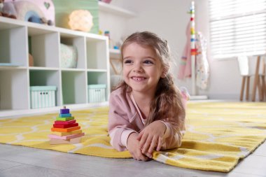 Mutlu küçük kız oyun odasında yerde yatıyor.