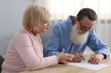 Ahşap masada son arzuları ve vasiyetnameleri imzalayan yaşlı çift.
