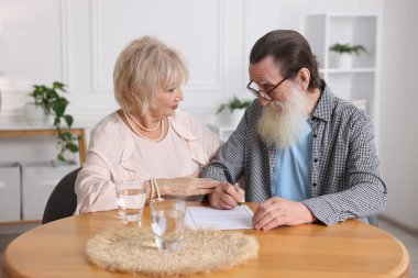 Ahşap masada son arzuları ve vasiyetnameleri imzalayan yaşlı çift.