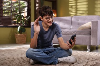 Genç çocuk evde akıllı telefondan görüntülü konuşma yapıyor.