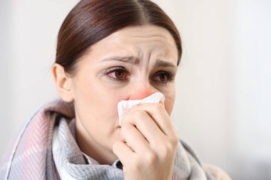 Evde soğuktan acı çeken dokusu olan bir kadın. Kırmızı gözler ve burun.