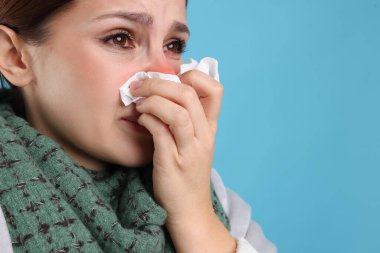 Açık mavi arka planda soğuktan acı çeken, dokuları olan hasta bir kadın. Kırmızı burun ve gözler.