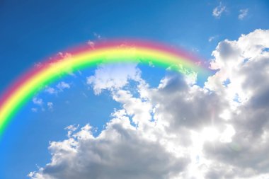Parlak renkli gökkuşağı ve mavi gökyüzündeki bulutlar