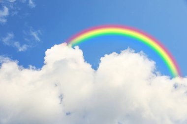 Parlak renkli gökkuşağı ve mavi gökyüzündeki bulutlar