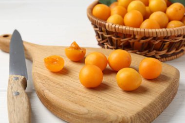 Olgun sarı kiraz erikleri ve bıçak beyaz ahşap masada, yakın plan.